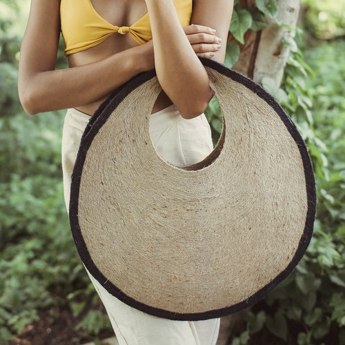 Person holding a woven bag with a natural background