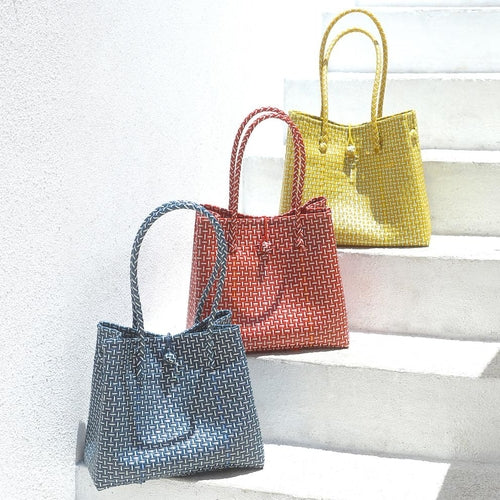 Four woven handbags in blue, red, yellow, and multicolor on a white surface.