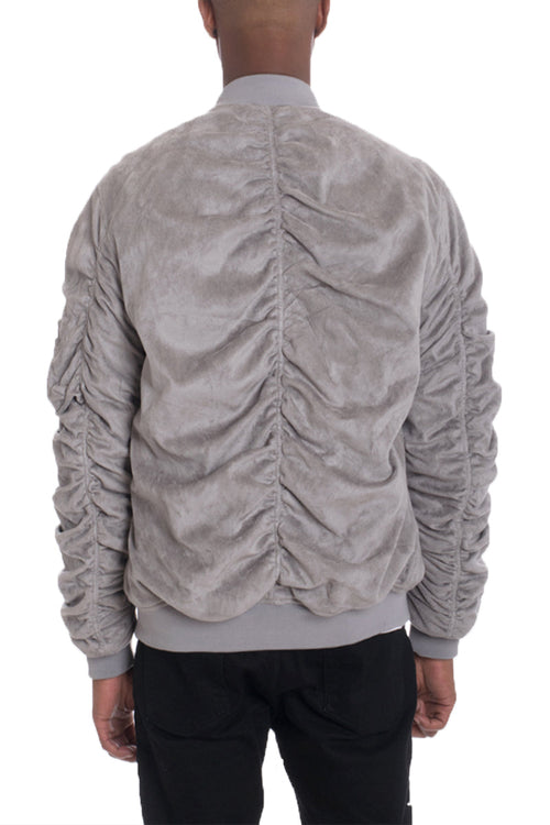 Back view of a person wearing a gray ruched jacket on a white background