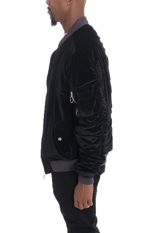 Black velvet bomber jacket worn by a person on a white background