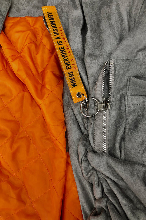 Close-up of a gray jacket with an orange interior and a yellow zipper pull.