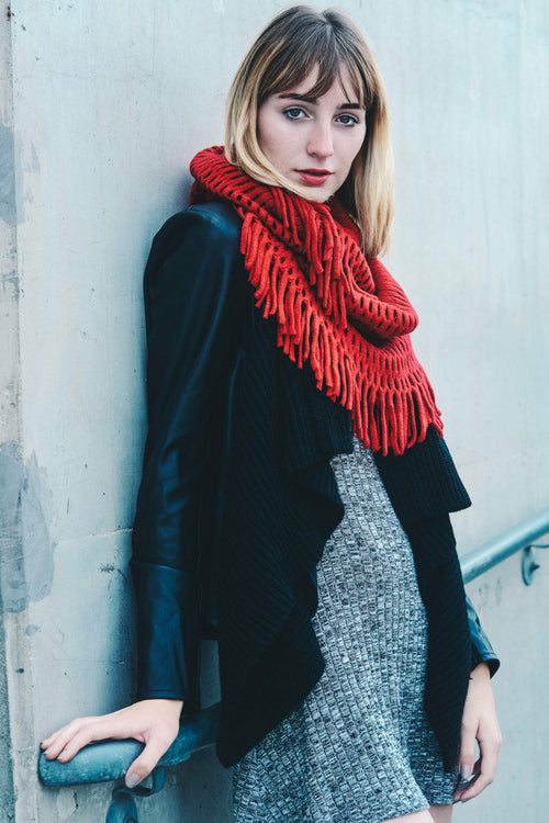 Woman wearing a red scarf and black coat against a gray wall