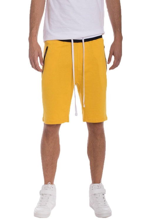 Person wearing yellow shorts and white sneakers on a white background