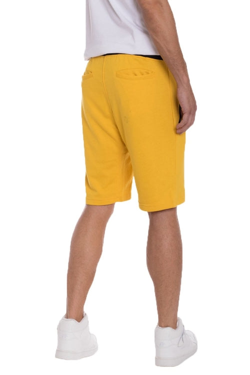 Person wearing yellow shorts and white shoes on a white background