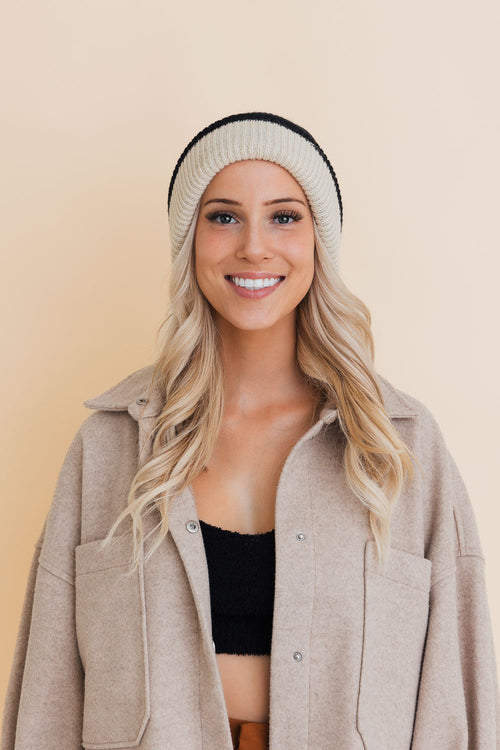 Woman wearing a beige beanie and coat against a beige background