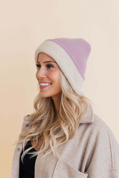 Woman wearing a two-tone beanie with a beige and purple gradient on a beige background