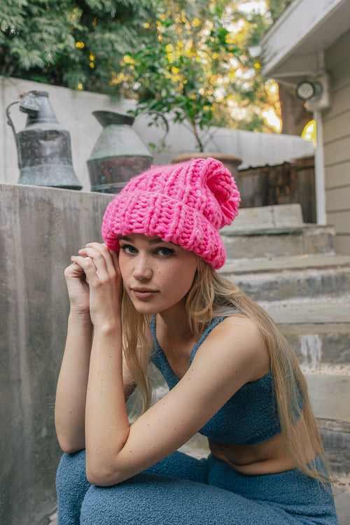 Woman wearing a pink knit hat sitting on steps outdoors