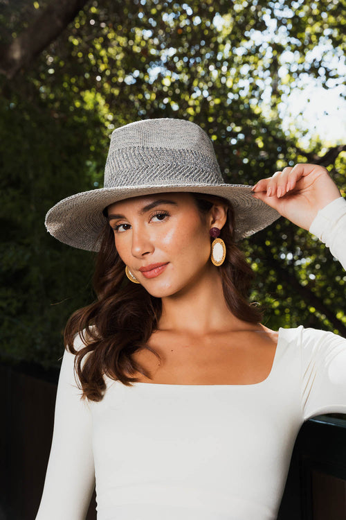 Woman wearing a gray fedora hat with a blurred green background