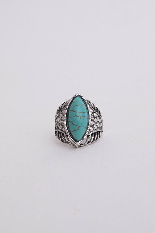 Turquoise stone ring with silver band on a light gray background