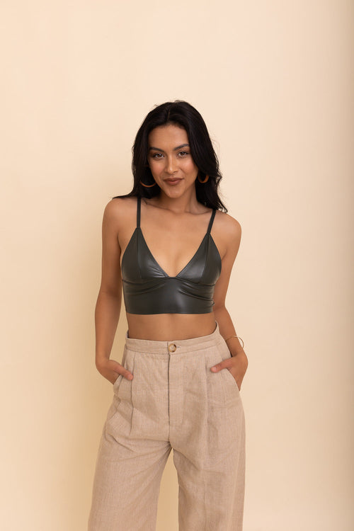 Woman wearing a black leather top and beige pants against a beige background