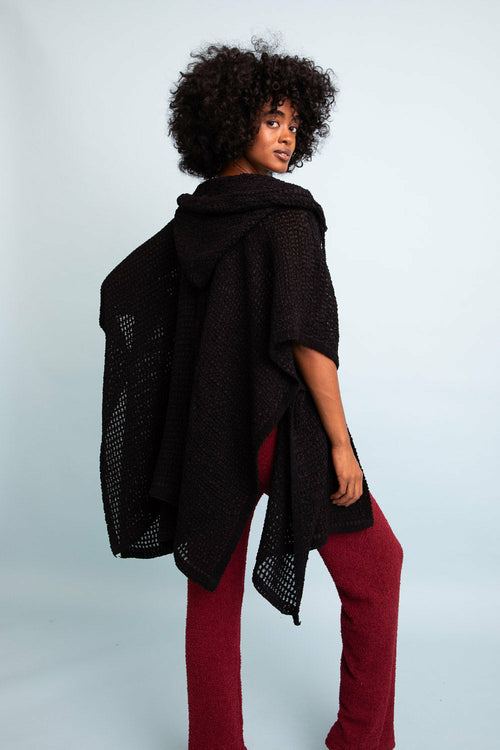 Woman wearing a black shawl over a red outfit against a light gray background