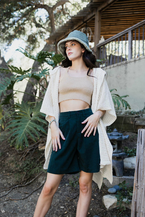 Woman wearing a beige top, green skirt, and straw hat outdoors.