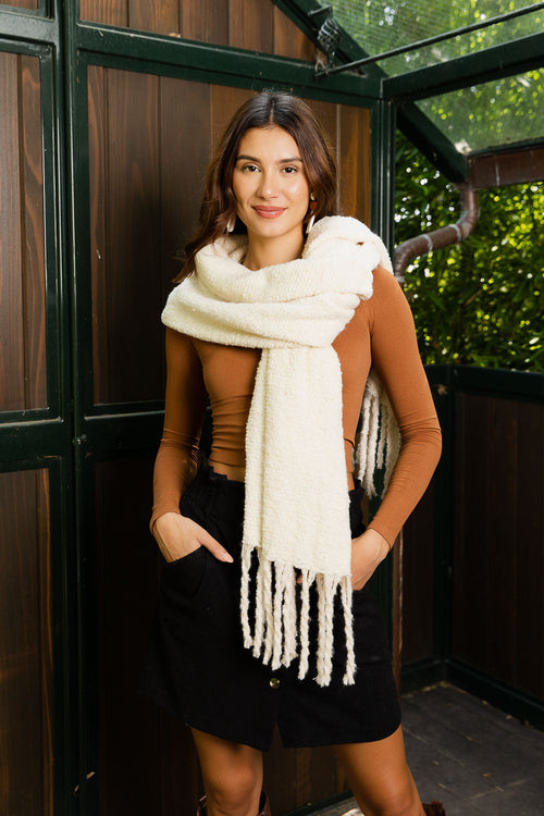 Woman wearing a white scarf with a brown top and black skirt in an outdoor setting.