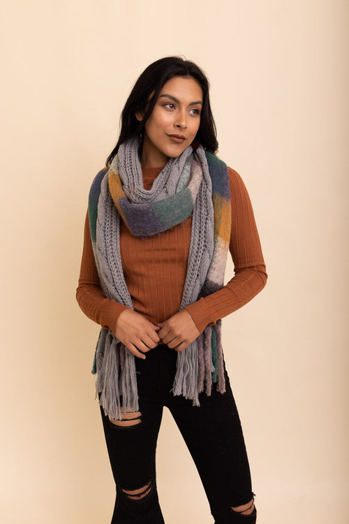 Woman wearing a colorful scarf and brown sweater against a beige background
