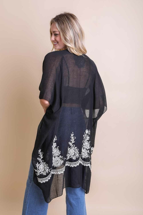 Woman wearing a black sheer kimono with white lace details on a beige background