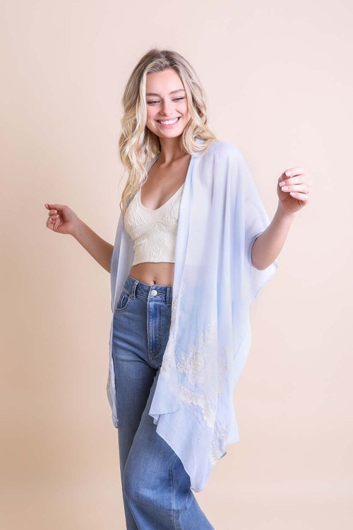 Woman wearing a light blue scarf over her shoulders against a beige background