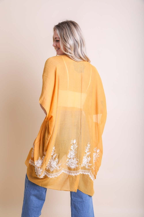 Woman wearing a yellow lace-trimmed top against a beige background