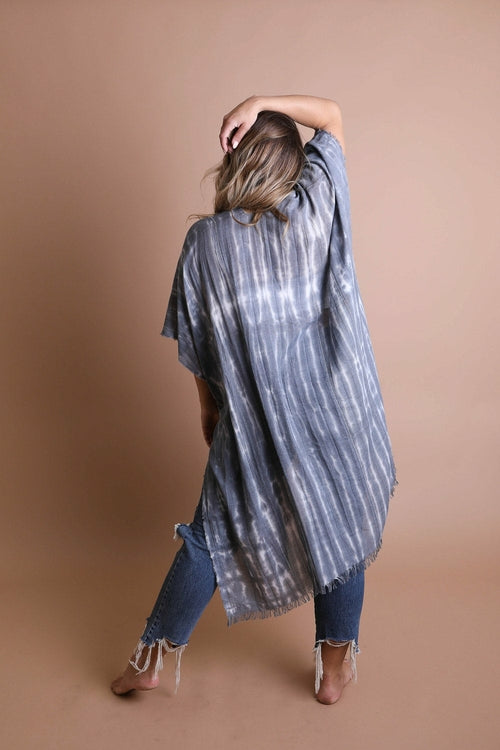Woman wearing a long, light-colored striped kimono against a brown background