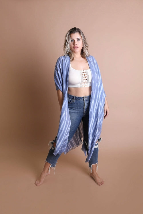 Woman wearing a blue striped kimono over a white top and jeans on a beige background