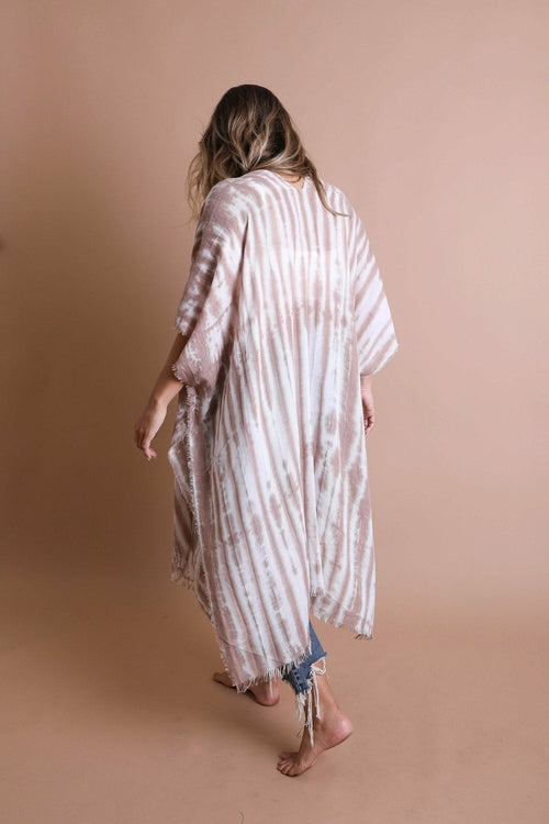 Person wearing a long, light-colored tie-dye kimono against a beige background