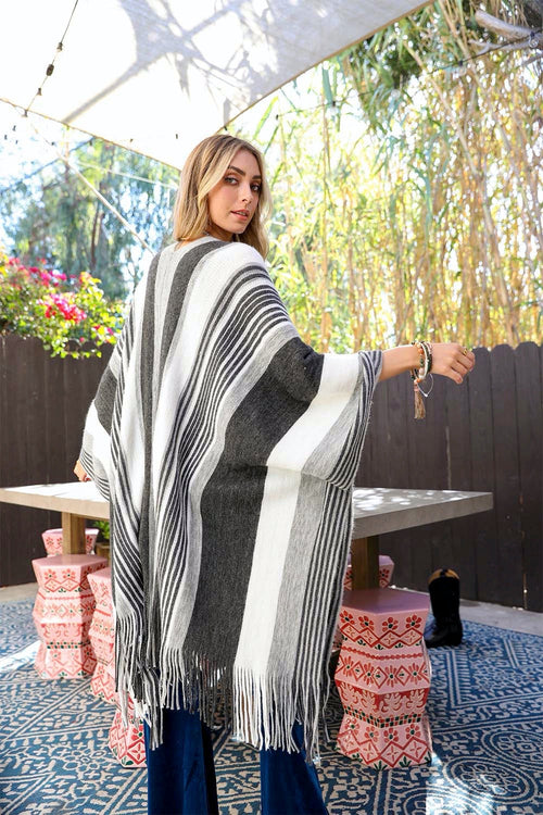 Woman wearing a black and white striped poncho in an outdoor setting