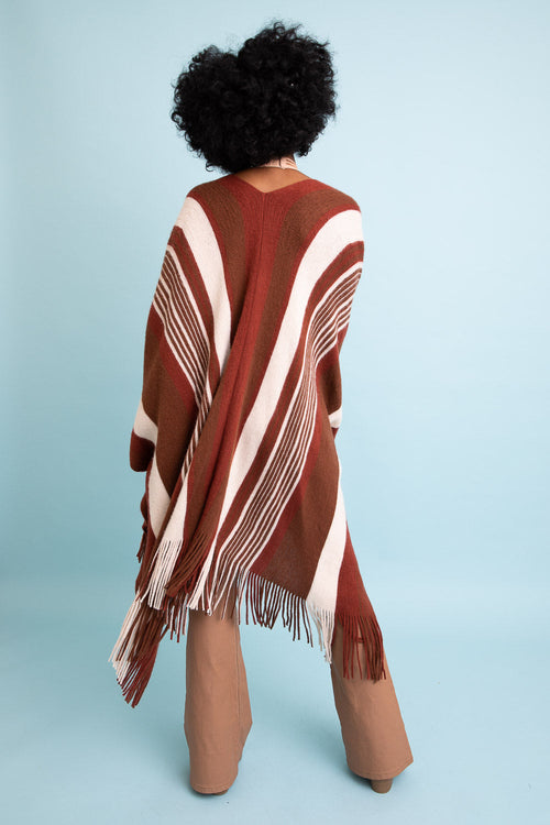 Person wearing a brown and white patterned poncho against a light blue background