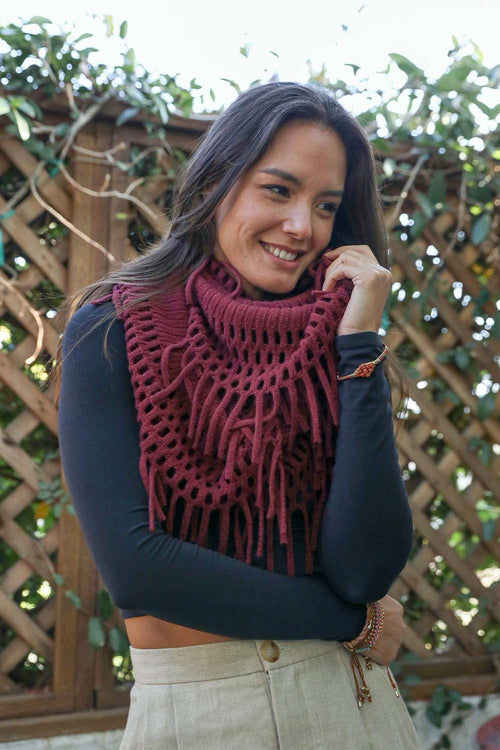 Woman wearing a dark blue sweater and maroon knitted scarf against a wooden lattice background