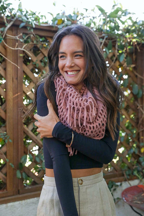 Woman wearing a pink knitted scarf and navy sweater in an outdoor setting