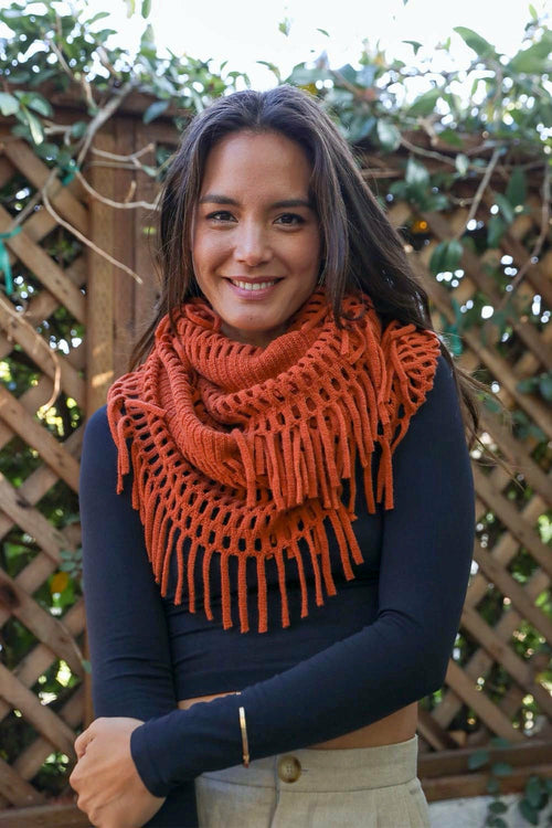 Woman wearing an orange knitted scarf with a wooden lattice background