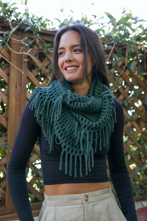 Woman wearing a green knitted scarf with a blurred natural background