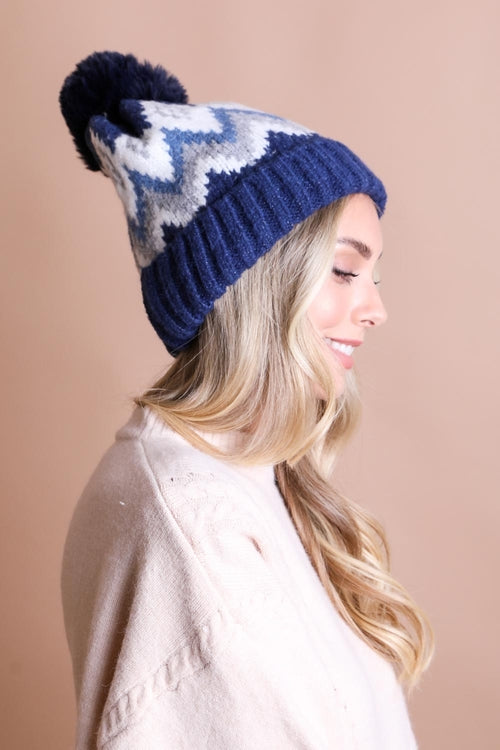 Woman wearing a blue and white patterned knit beanie against a beige background