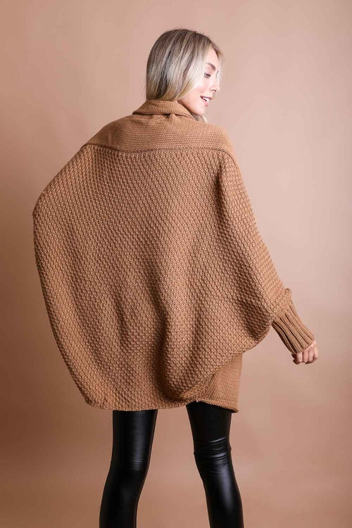 Person wearing a brown oversized sweater against a beige background