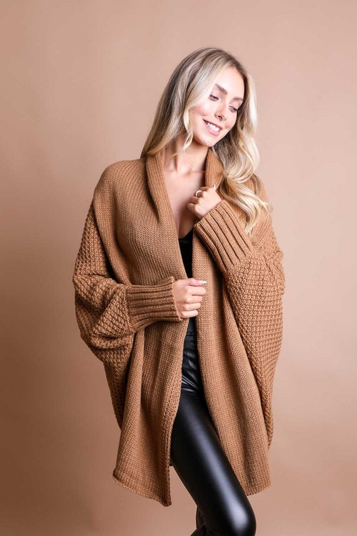 Woman wearing a brown knitted cardigan against a beige background