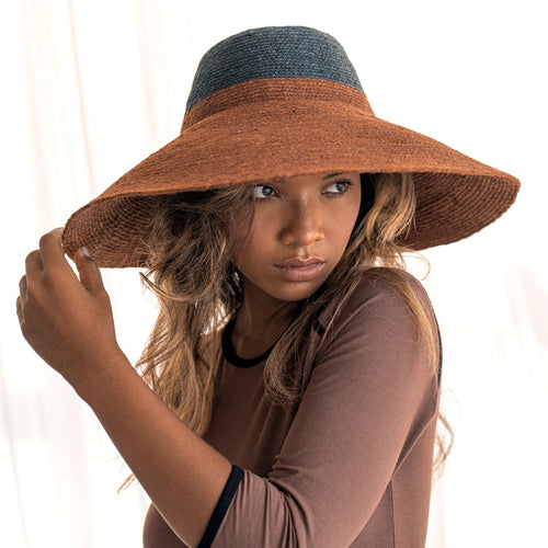 Woman wearing a large brown hat with a white background