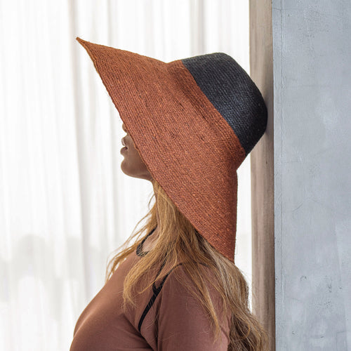 Person wearing a two-tone brown and black hat against a neutral background