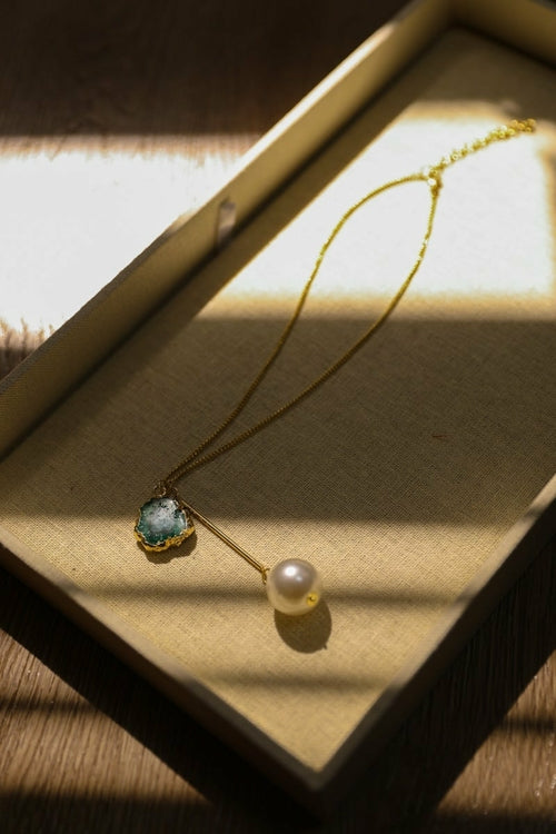 Necklace with a pendant and pearl on a textured surface