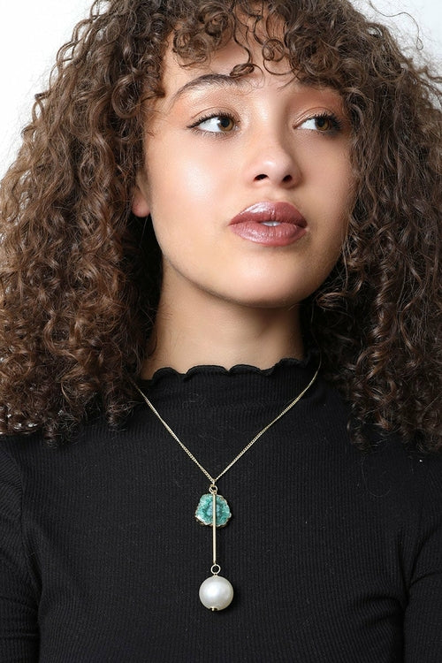 Woman wearing a necklace with a pendant against a neutral background