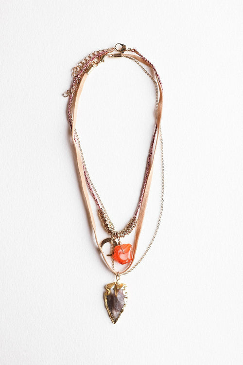 Layered necklace with gemstone pendants on a white background