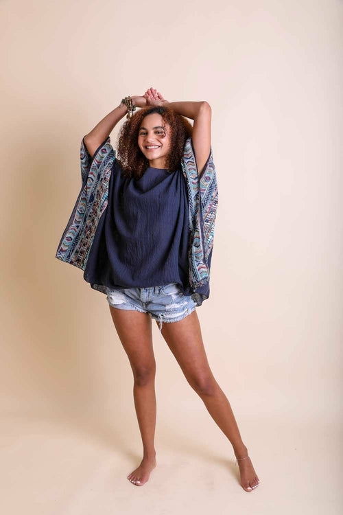 Woman wearing a navy top and patterned kimono over a beige background