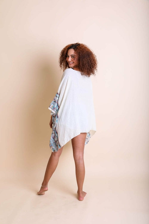 Woman wearing a white dress with floral sleeves against a beige background