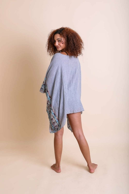 Woman wearing a light blue poncho over a floral dress on a beige background