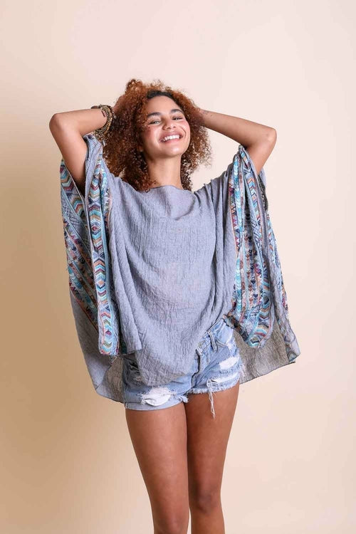 Woman wearing a gray oversized shirt with a colorful patterned kimono over it on a beige background