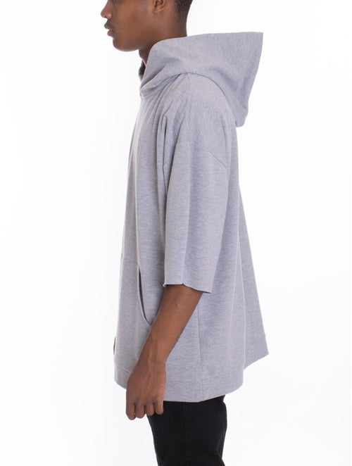 Person wearing a gray hooded garment on a white background