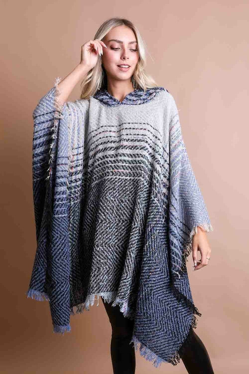 Woman wearing a blue and gray patterned poncho against a beige background