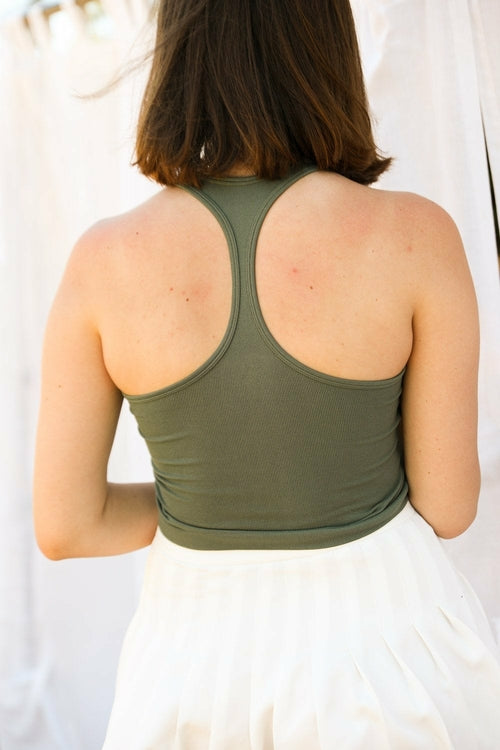 Person wearing an open-back green top with a blurred background