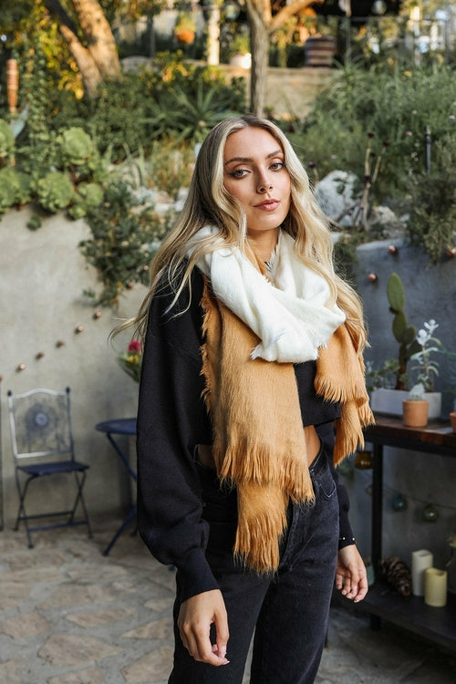 Woman wearing a brown fringed scarf in an outdoor setting