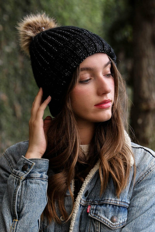 Woman wearing a black knit beanie with a pom-pom in a forest setting