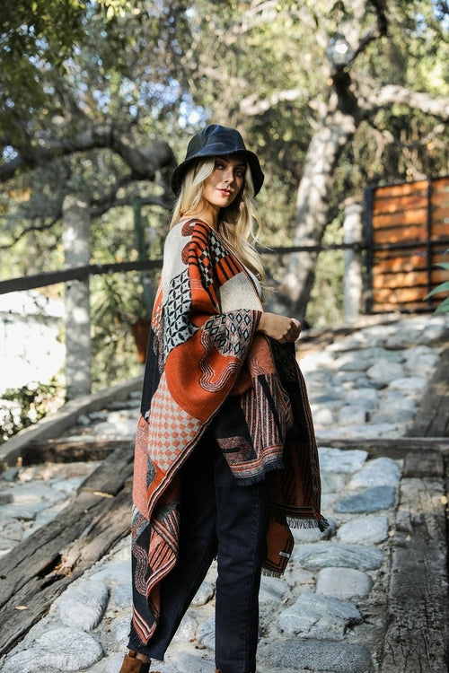 Woman wearing a patterned shawl and hat in a natural setting