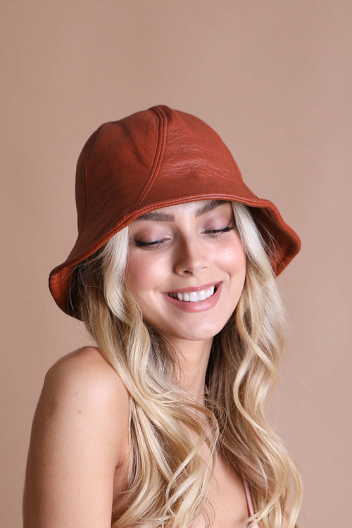 Woman wearing a brown bucket hat against a beige background