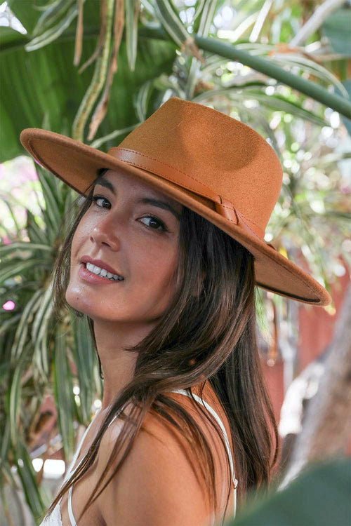 Woman wearing a brown hat in a natural setting with plants